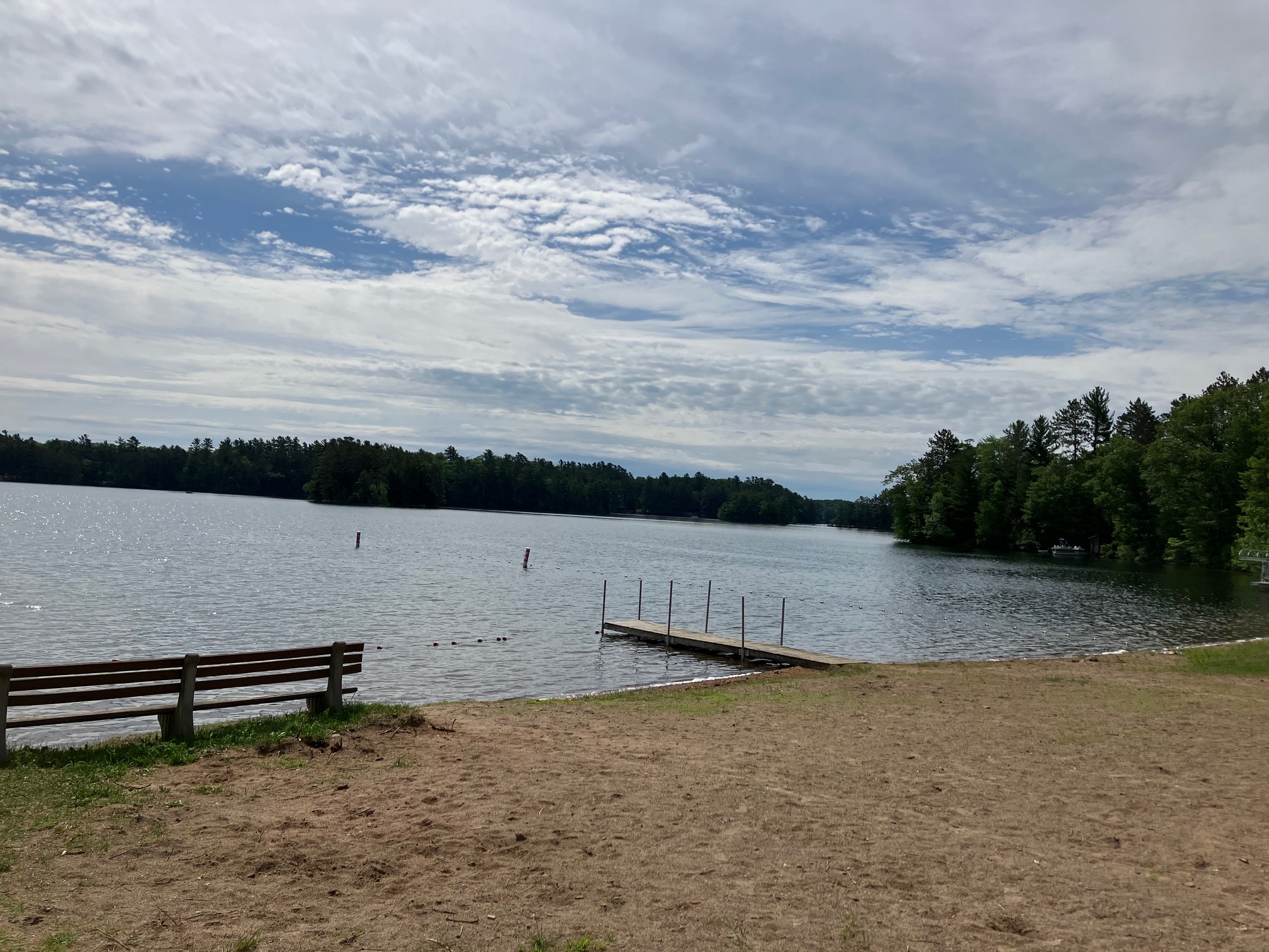 A sunny afternoon at a clear Northwoods beach with a wooden dock